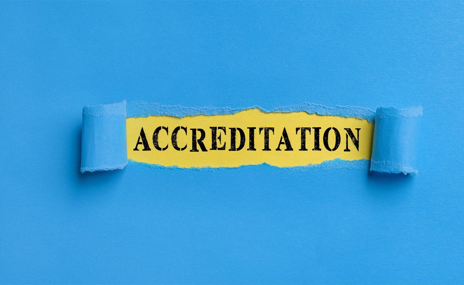 Torn paper strip on blue background saying accreditation